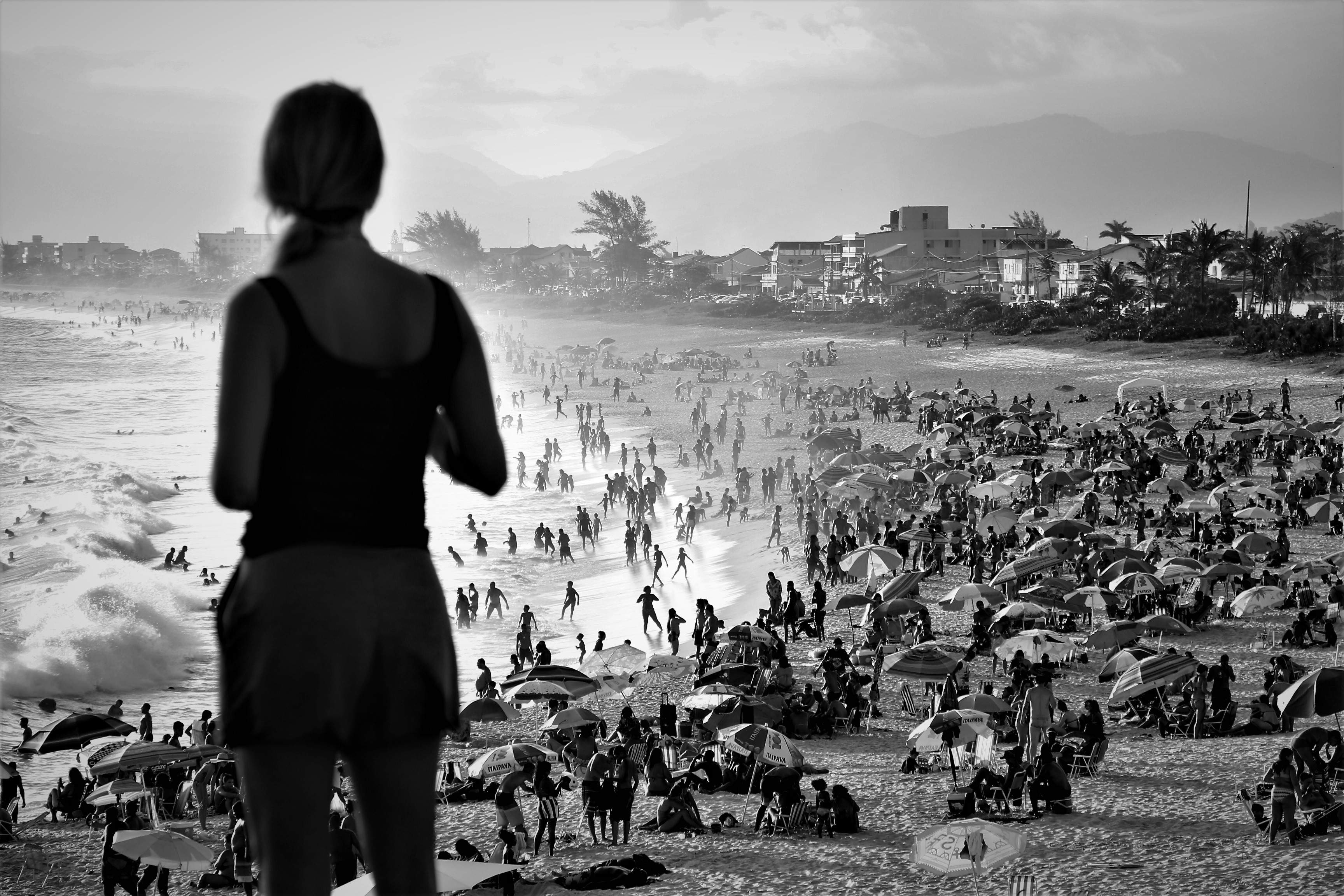 Mulher olha para praia lotada